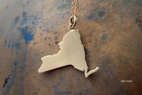 Silhouette pendant necklace in 18K gold with matte finish and Manhattan border