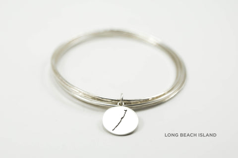 Stack of sterling silver hammered bangles featuring round Long Beach Island border with matte finish.